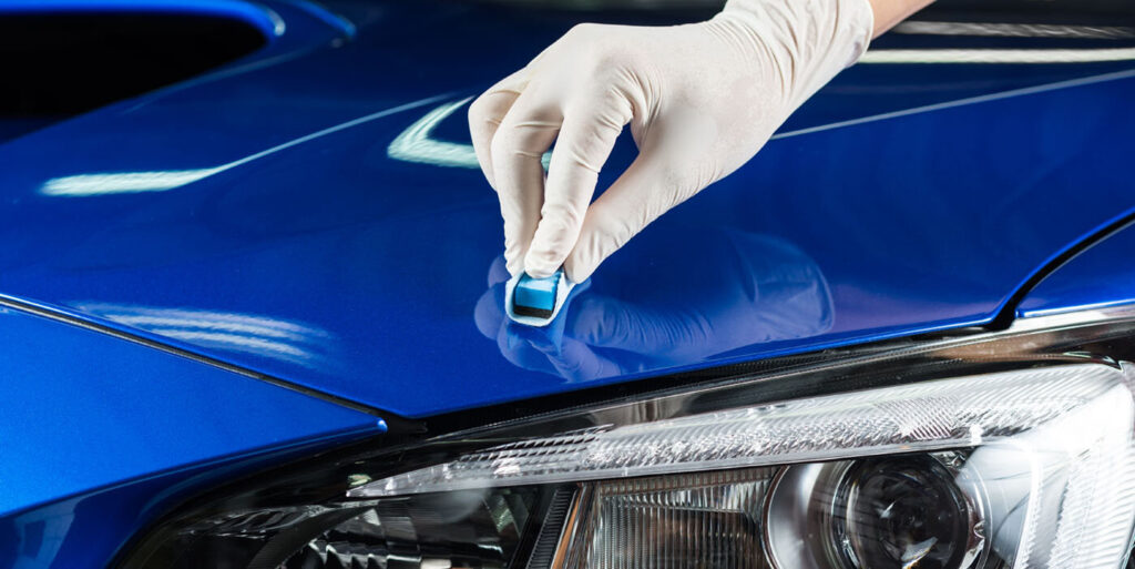 Car detailing series : Closeup of hand coating blue car bonnet